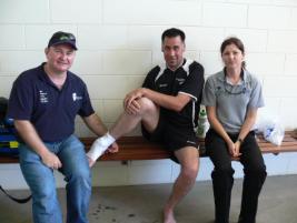 PhotoID:13356, CQUniversity Paramedic lecturer Paul Oliveri (left) and Paramedic Science student Nirvana Stewart treat New Zealand Soccer team captain Hayden Smith at the Trans Tasman Special Olympics tournament. 