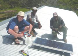 PhotoID:7610, A team member helps locals install a solar panel