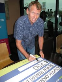 PhotoID:9706, Associate Professor Peter Reaburn signs the cheque to be presented to the Sporting Wheelies.