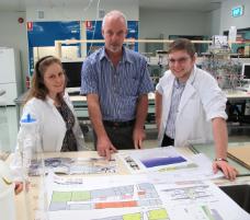 PhotoID:11305, Infrastructure planner Graeme Boyle (centre) shows PhD students Rebecca Vella and Douglas Jackson over the latest allied health clinic plans