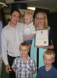 PhotoID:10893, Natalie Wright shows off her graduation certificate alongside her supportive family at the Gladstone graduation ceremony.